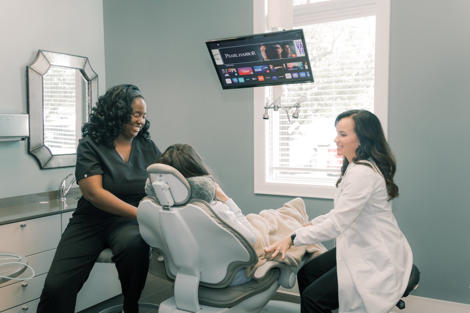 A dentist and patient sitting beside a patient in a dental chair