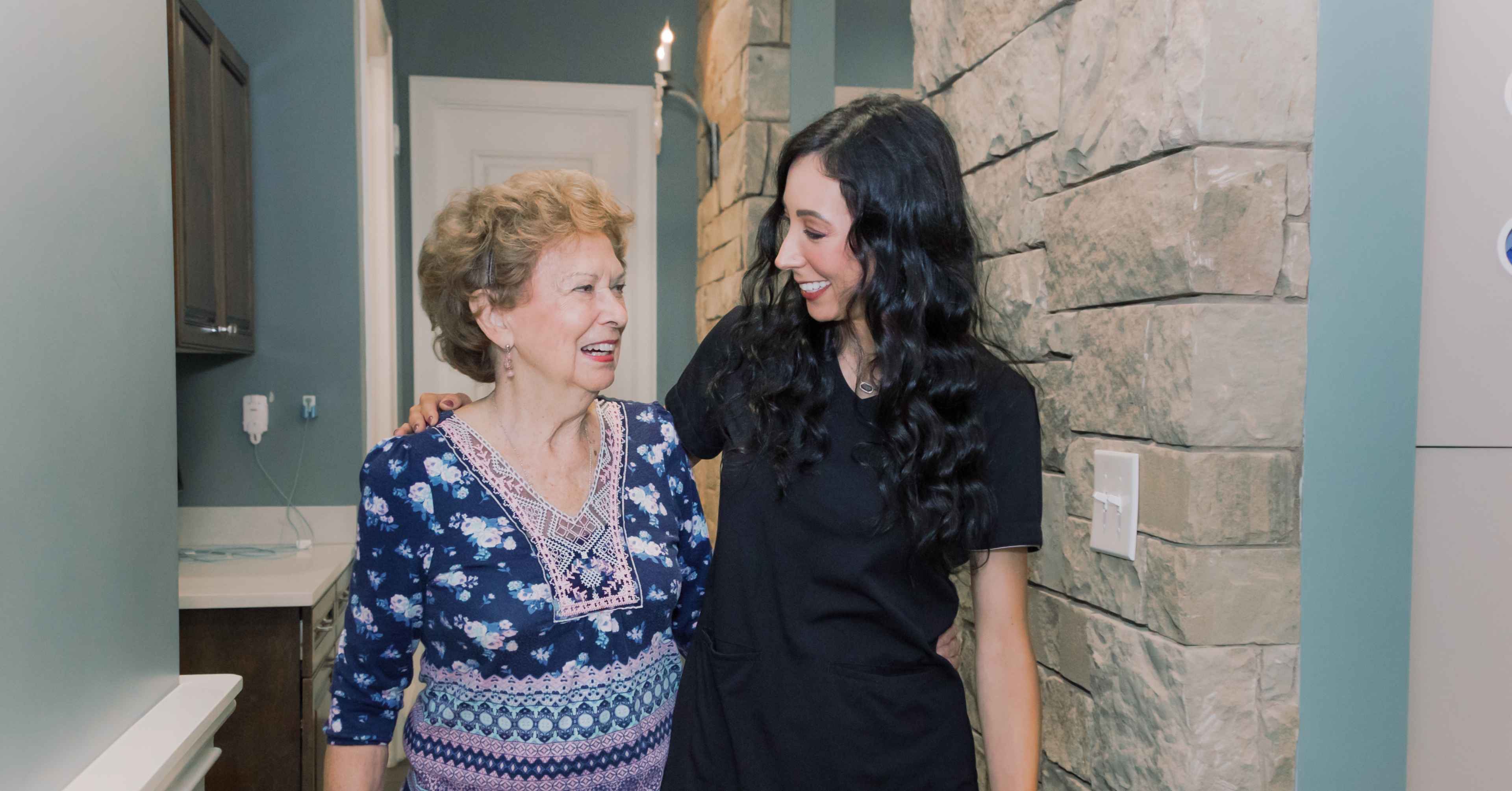 A team member walking with her arm around an elderly patient