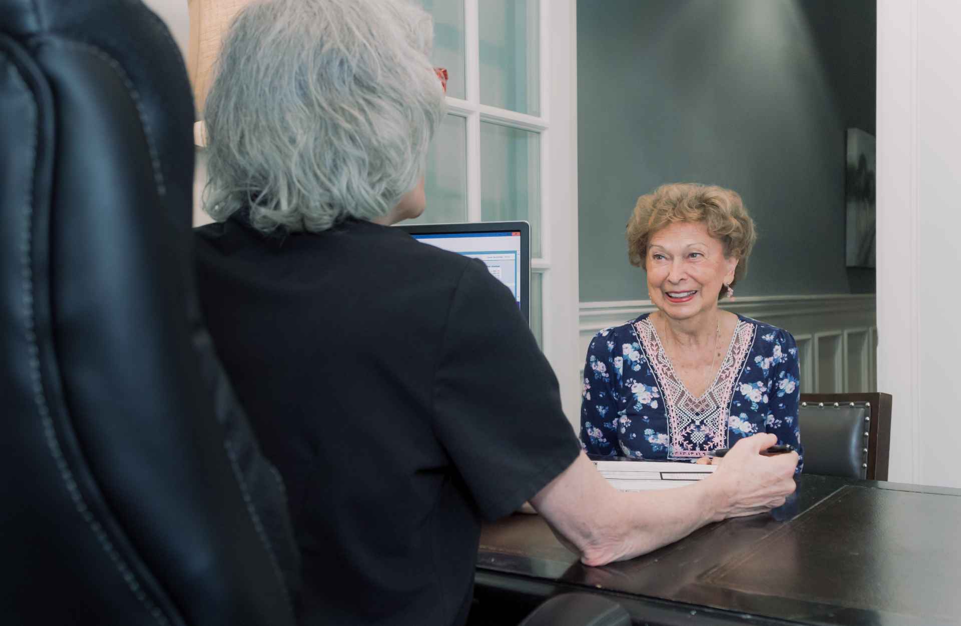 An elderly patient talking with a team member at a desk