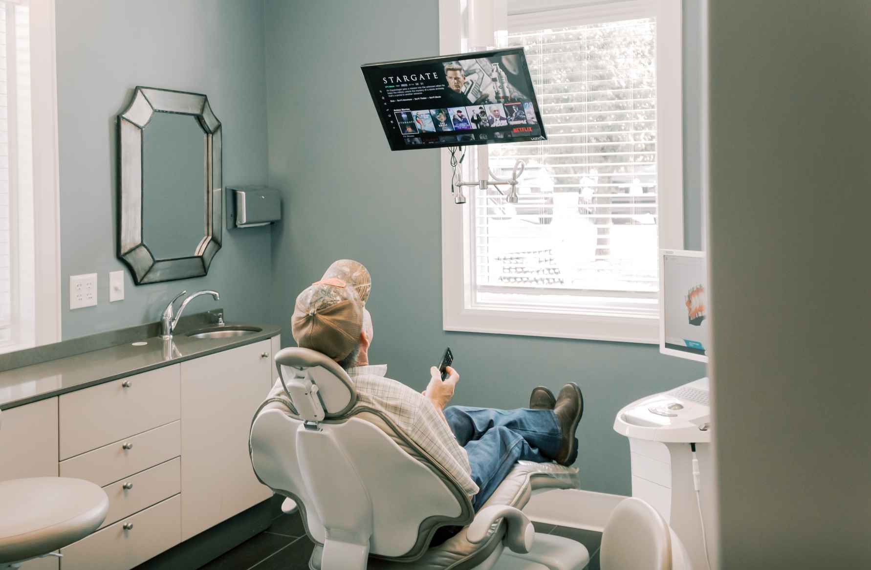 A patient sitting in a dental chair looking up at a television